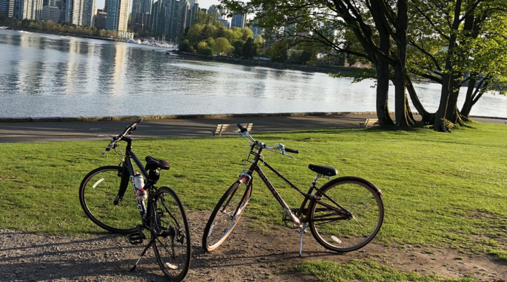 Two bicycles parked by the water in a Vancouver park near YesCycle's Denman Street rental shop